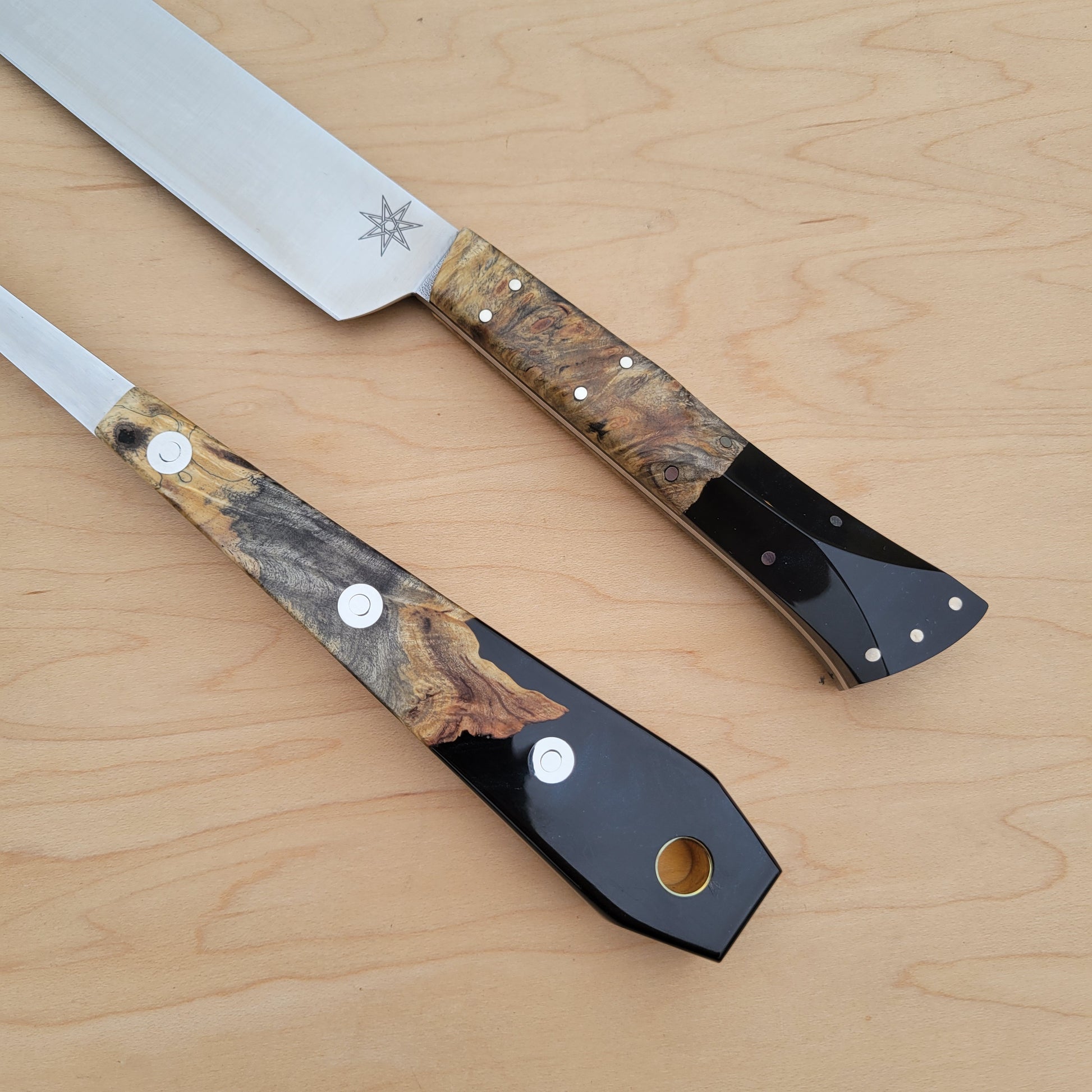 Two knives with decorative handles on a wooden surface