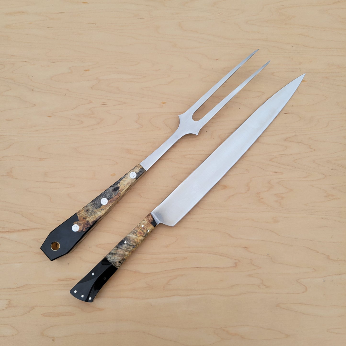 Two metal carving utensils with decorative handles on a wooden surface