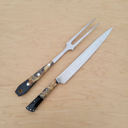 Two metal carving utensils with decorative handles on a wooden surface