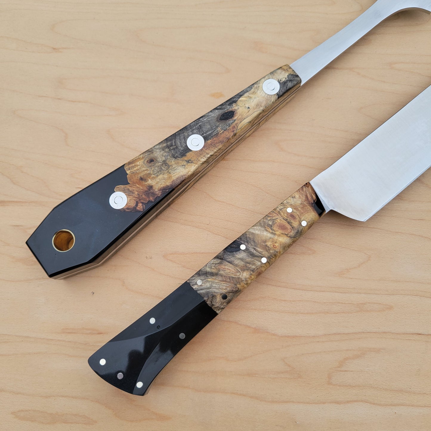 Two knives with decorative handles on a wooden surface