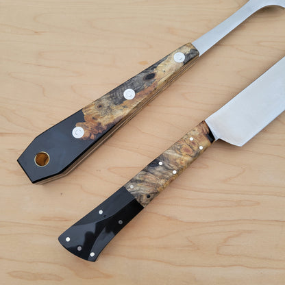 Two knives with decorative handles on a wooden surface