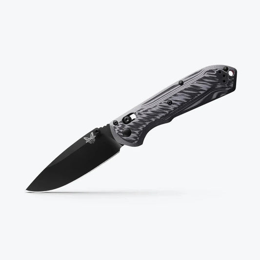 Folding knife with black blade and camouflage handle on a white background