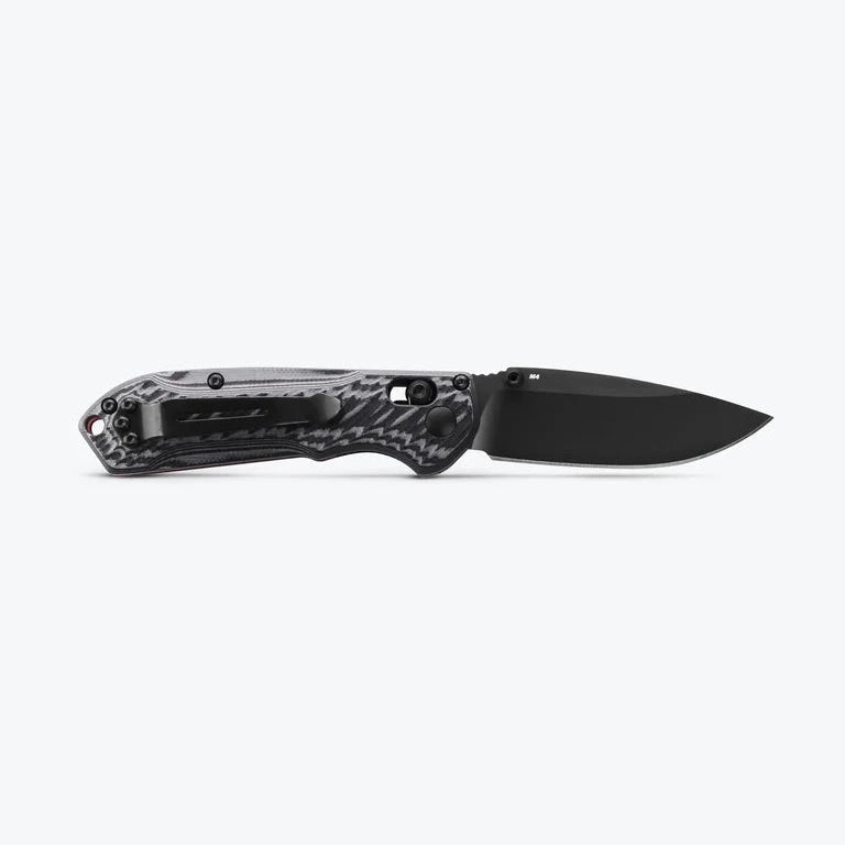Black folding knife with a carbon fiber handle on a white background